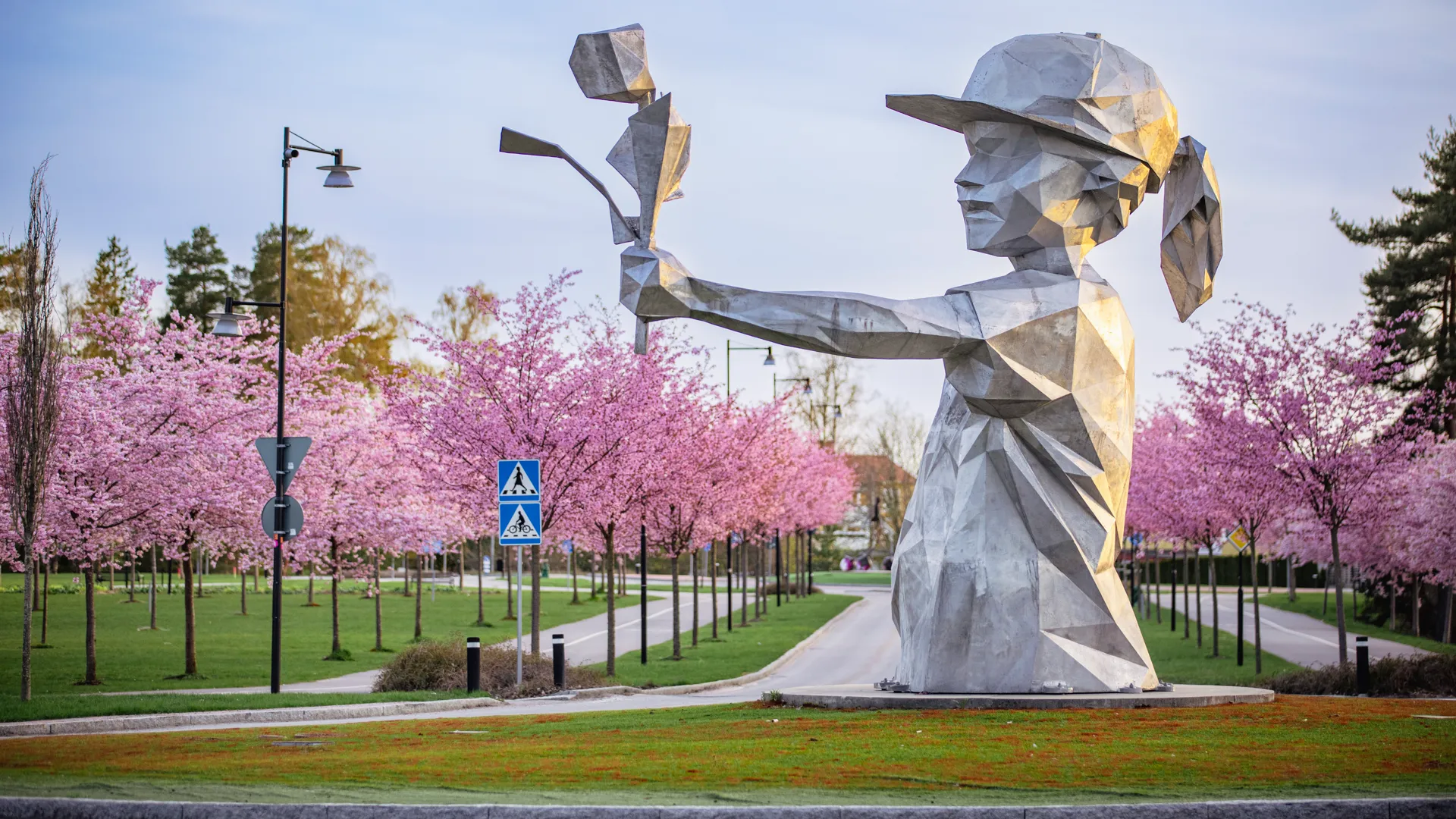En staty av en kvinna som håller en lampa i en park.