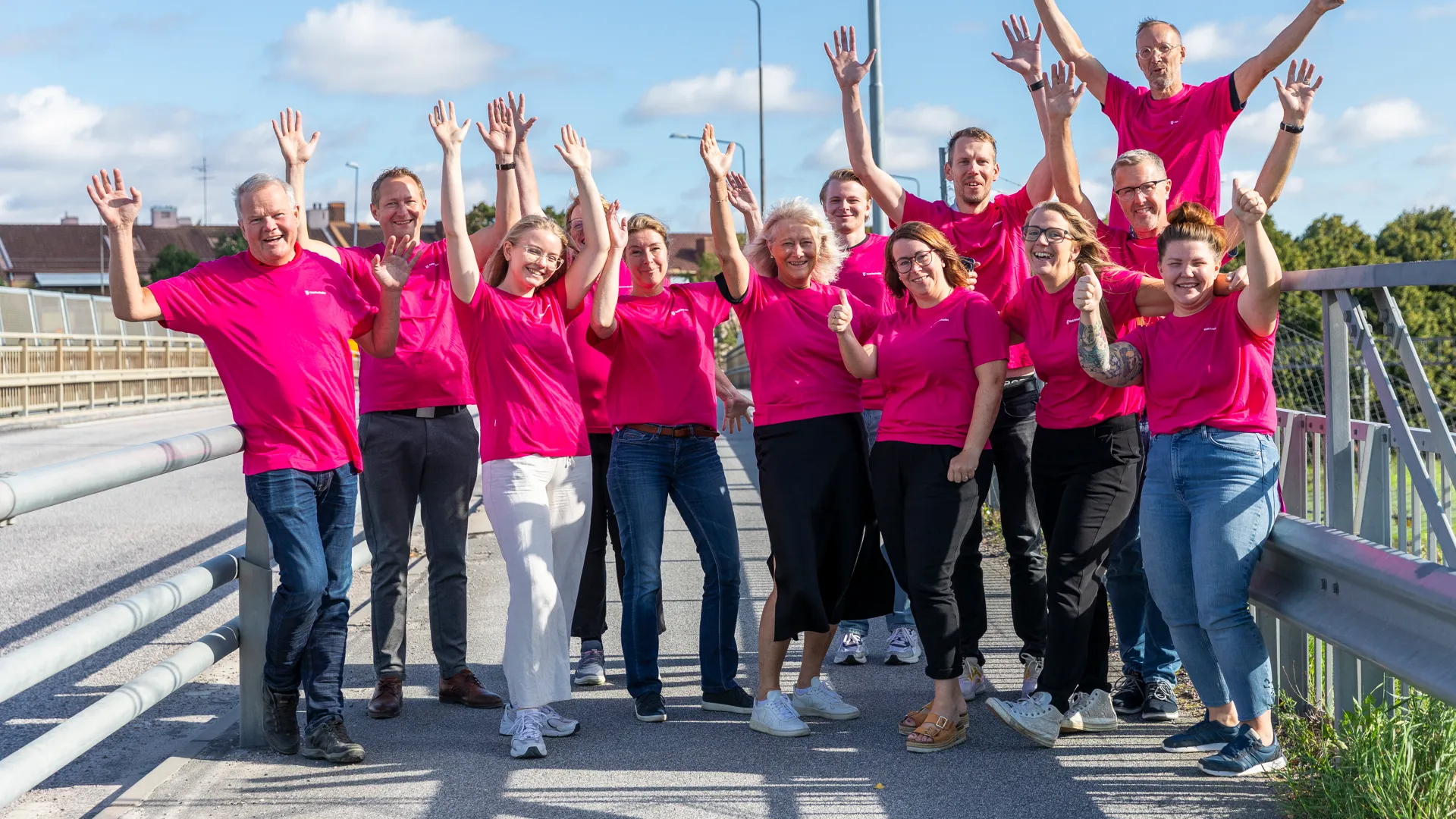 En grupp människor i rosa skjortor som står på en bro.