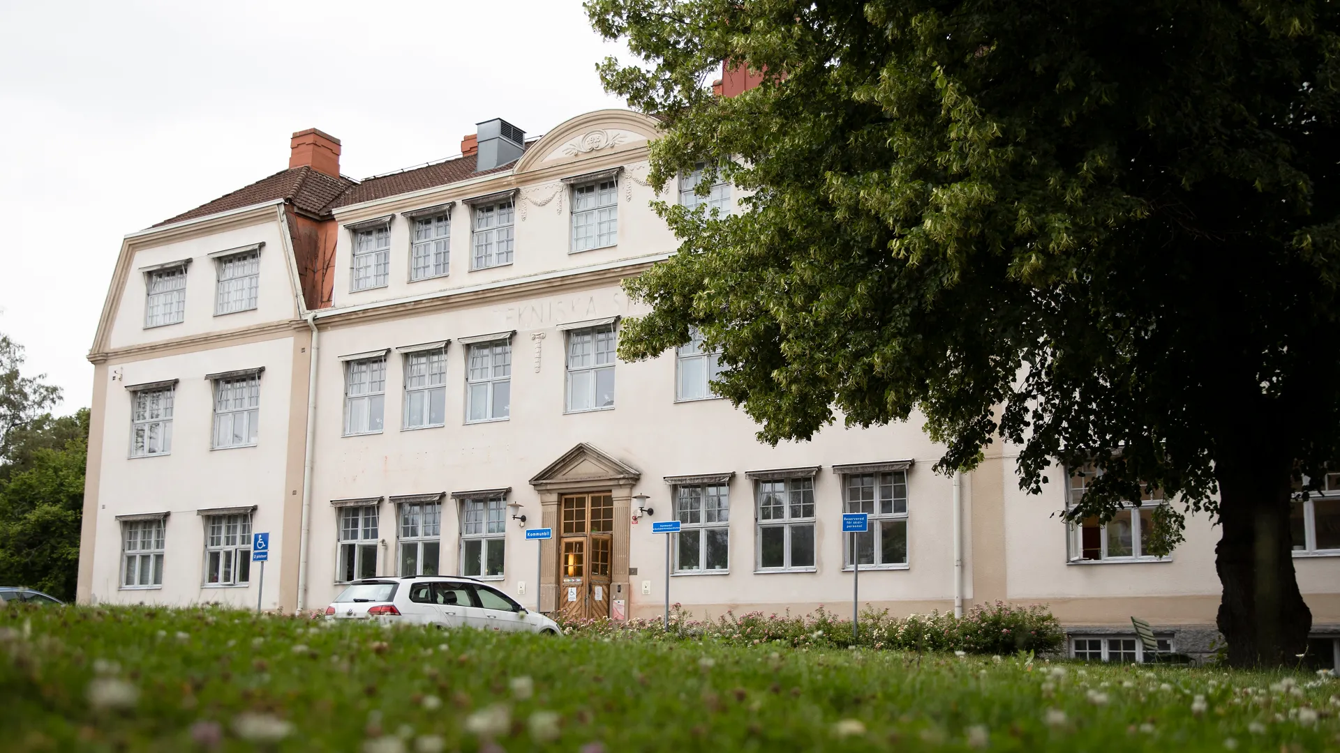 En stor vit byggnad med en bil parkerad framför.