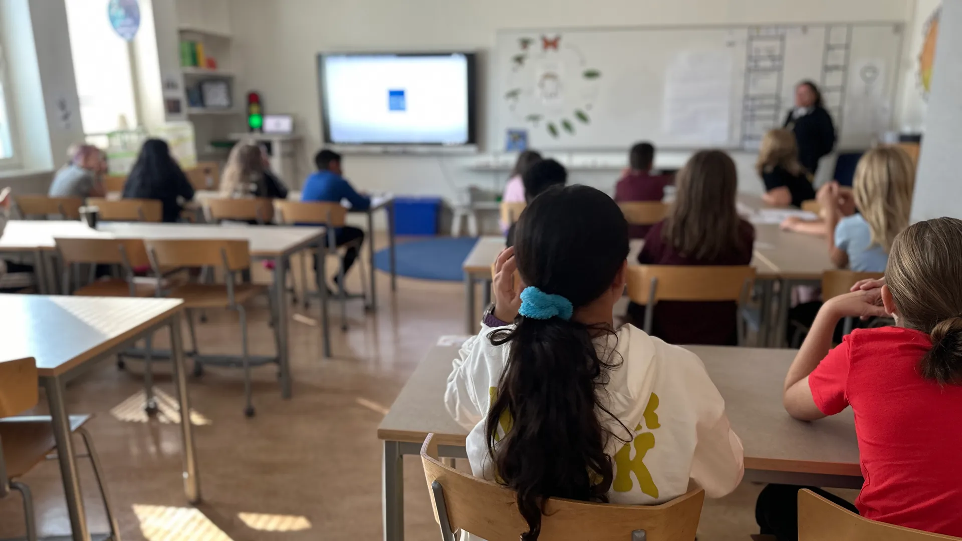 En grupp barn som sitter vid sina bänkar i ett klassrum.