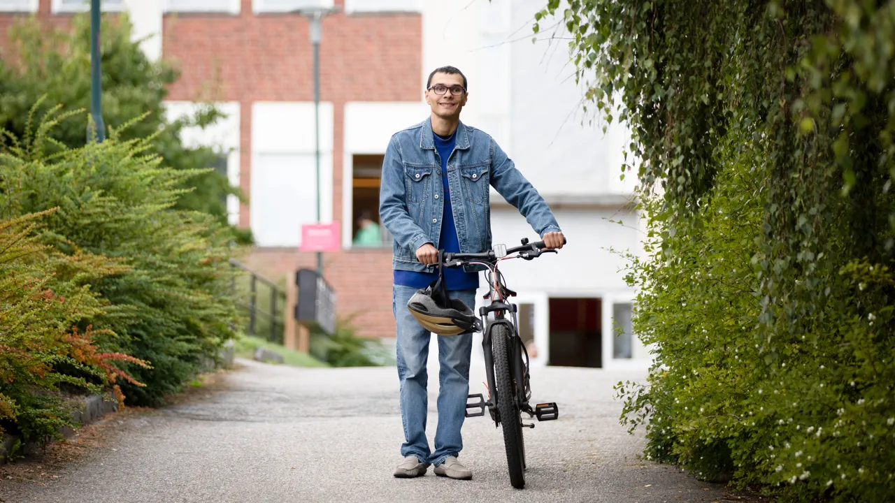 En man som står bredvid en cykel på trottoaren.